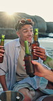 Picnic, man and cheers with beer at beach, social gathering and relax on summer vacation. Toast, drinks and friends outdoor for celebration by ocean, holiday hangout or happy with sunshine at reunion
