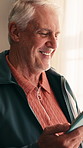 Online, tablet and old man in home with laugh, funny news update and notification for social media. Happy, senior person and relax by window with tech, internet meme or thinking of text message joke.