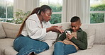 Mom, conversation and child with phone on sofa for bad behavior, distraction or discipline. Black family, mom and talking with son or kid on smartphone for communication, concern or advice in house