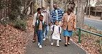 Family, walking and generations outdoor for bonding, relationship and trip in town with talking. Black people, grandparents and parents with children on sidewalk, conversation and travel together