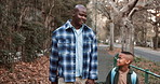 Father, walk and holding hands outdoor with school child, discussion and tips for education goals. Black man, son and conversation in neighborhood with support, learning advice or commute to academy.