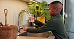 Health, kid and glass of water with faucet in home for wellness, nutrition benefits and development. Thirsty black boy, hydration and pour clean liquid with tap, minerals and growth at kitchen
