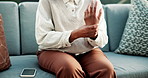 Hands, woman and massage on sofa with wrist pain, inflammation and symptoms for carpal tunnel. Female person, discomfort and phone at house with muscle stiffness, rheumatic disease and pinched nerve