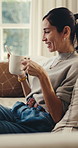 Laugh, phone and woman on sofa with coffee, online communication and comic post on social media. Happy, bokeh and mature person in house with warm drink, funny text and meme reaction on chat app.