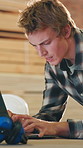 Man, carpenter and typing with laptop in warehouse for lumber project or shipping schedule. Male person, carpentry and research with computer for timber project, distribution or wood production