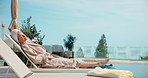 Woman, relax or vacation with chair in luxury resort for holiday getaway or summer break by poolside. Female person, travel or rest with sunshine or tan by swimming pool for weekend retreat on space