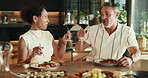 Couple, cheers and dining with wine glass in home for romantic date, dinner or meal together. Man, woman or toast with alcohol, food or drink for honeymoon celebration, event or holiday in house