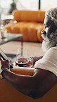 Tablet, wine and mature man on sofa for internet, social media and relax with drink on weekend. Happy, home and black person on digital tech with alcohol for rest, website and reading ebook on break