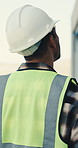 Engineer, inspection and man walk at construction site with helmet, property evaluation and review. Back, supervisor and person outdoor with PPE for building assessment, check infrastructure or plan.