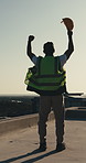 Celebrate, rooftop and man with helmet for construction, building approval and fist pump outdoor. Excited, back and person with ppe for compliance success, feedback and good news for engineering