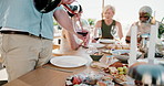 Friends, man and pour red wine on patio with lunch, summer vacation or get together on weekend break. Mature people, relax and alcohol outdoor with glass, food and social gathering for connection.