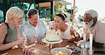 Smile, woman and friends at house with cake, blowing candles and celebration for birthday wish. Happy, mature people and cheers on patio with alcohol, dessert and social gathering on special occasion