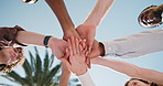 People, meeting and friends with hands together in park for mission, social cohesion or solidarity. Low angle, group or community piling with stack or blue sky for outdoor inclusion, trust or support