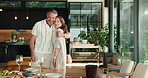 Couple, hug and laughing with meal in house, bonding and setting table with partner on special day. Mature people, embrace and preparing for dinner party with spouse, happiness and connection in home