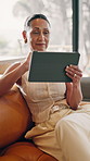 Woman, tablet and relax on sofa with smile, online puzzle and down time hobby in living room. Mature person, technology and chill in home with ebook, media subscription and reading with scroll
