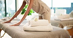 Hands, woman and bed at spa with towel, massage preparation and cleanliness for hospitality. Masseuse, organizing and housekeeping at resort with fresh linen, arrangement and luxury treatment