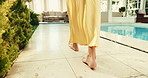 Woman, feet and walk at resort with swimming pool, travel and peaceful summer holiday for wellness. Person, legs and relax at luxury hotel with vacation, hospitality and tranquility for spa getaway.