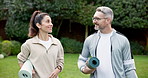 Couple, fitness and walking with yoga mat in nature for outdoor discussion on workout routine. Active, man or woman talking with smile or chat for morning wellness, mindfulness or health in park 