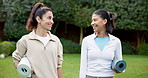 Women, fitness and walking with yoga mat in nature for outdoor discussion on workout routine. Active, female people or friends talking with smile for morning wellness, mindfulness or health in park 