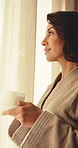 Woman, thinking and coffee in hotel with window, morning reflection and travel for peaceful vacation. Mature person, planning holiday and calm in accommodation with warm drink, tranquility or vision.