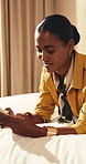 Woman, relax and typing in hotel room with phone, tourist vacation and update social media on trip. Happy, person and rest in lodge with mobile tech, holiday and reading online post on travel blog.