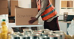 Hands, person and donations in box for volunteering, food drive and non profit of charity outreach. Man, stock and collection in cardboard with groceries, pantry goods and package for poverty relief