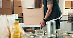 Hands, volunteer and box in office with donations, food drive and non profit of charity outreach. Person, stock and collection in cardboard with groceries, pantry goods and package for poverty relief