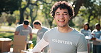 Man, volunteer and face in nature with box, campaign and happy for community outreach program. NGO, humanitarian and team in park for food drive, social responsibility or donation project for charity
