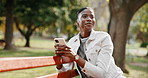 Phone, text and happy woman at park, thinking and funny response for online dating on vacation. Mobile, relax and black person on bench in nature for reflection, laugh or match connection on holiday