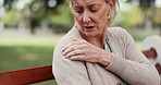 Mature, woman and shoulder pain on park bench for injury, discomfort or muscle tension in nature. Female person, massage or sore arm with stress or ache for fibromyalgia, pressure or outdoor strain