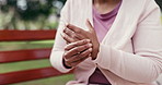 Mature, woman and hands with wrist pain on park bench for injury or carpal tunnel syndrome. Female person, massage or sore arm with discomfort for fibromyalgia, muscle tension or strain in nature