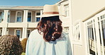 Woman, travel and summer with hotel for holiday getaway, weekend stay or vacation in villa. Back view, female person or traveler walking with hat for accommodation in luxury retreat, estate or resort