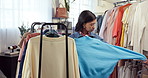 Shopping, rack and woman in store with clothing, outfit search and decision in trendy style. Retail, sweater and customer in boutique with selection, garment choice and option for fashion purchase.