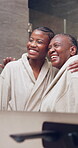 Woman, hug and senior mother in mirror for self care in bathroom with love, bathrobe and beauty. Black family, pamper and happy in house with affection, glow or quality time together for wellness