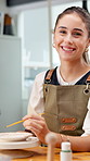 Face, woman and painting in art studio with clay dish, creative expression and smile for DIY project. Happy, person and artist in workshop with paintbrush, ceramic decoration and talent for craft.