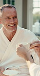 Coffee, cheers and senior man in spa, retirement and laugh with warm beverage on vacation and chill. Resort, guest and happy retired person with tea, toast and conversation with drink on holiday