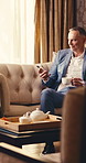 Hotel, coffee and businessman with phone, texting or communication with contact on social media app. Business travel, senior financial officer and happy person with mobile, chat and thoughts with tea