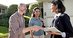 Couple, realtor and handshake at new home with tablet, agreement or success for property investment. Front yard, happy married people and shaking hands by house with real estate agent, tech and deal.