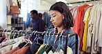 Shopping, search and woman in store with clothes, outfit review and decision in trendy style. Retail, check and customer in boutique with apparel rack, garment choice and option for fashion purchase.