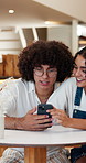 Phone, couple and talking at cafe on date, smile and share post on social media for connection. Mobile, happy man and woman at coffee shop with internet app, love and conversation with partner