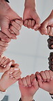 Below, fist and huddle with business people in office together for collaboration or solidarity. Effort, support and teamwork with employee group in workplace for commitment, connection or unity