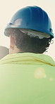 Man, electrician and helmet with safety for construction, system maintenance or repair service. Back view, male person or technician with blue hard hat for electrical power installation or fix 