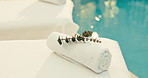 Towel, plant and pool with massage table in luxury resort for zen, accommodation or holiday getaway. Empty, leaves and fabric with cloth by poolside for hospitality, therapy or vacation in beauty spa