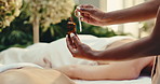 Person, hands and pipette with oil for massage, relaxation or luxury treatment on bed in beauty spa. Masseuse, drop and serum with vitamin C, zen or healing cosmetics for physical therapy in resort