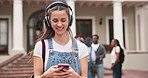 Woman, walk and phone in college with headphones, typing text message and listen to music playlist. Happy, person and student outdoor on university campus with audio tech, radio and social media.