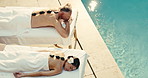 Spa, pool and couple with hot stones for back massage, muscle tension and wellness for bonding. Hospitality, anniversary and man with woman with heat therapy, treatment or pamper for romantic getaway
