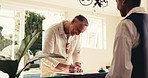 Travel, arrival and man in hotel with form, client information or booking details with check in. Happy, mature person or receptionist with signing, reservation process or verification in resort lobby