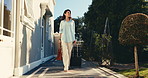Woman, walking and arrival at hotel with suitcase, check in and accommodation for holiday abroad. Mature person, ideas and outdoor with luggage, guest service and resort entrance for vacation getaway