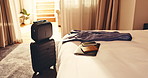 Hotel, travel and luggage in room with bed, passport and laptop electronics with phone on holiday. Resort, suitcase and accommodation interior for hospitality, tourism or motel furniture for vacation