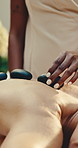 Hands, masseuse and woman at spa with hot stone, massage and treatment for muscle tension. Person, customer and skincare at salon with heated rocks, pain relief and thermal therapy for body wellness